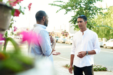 Happy two multiracial male best friends talking while standing in the street, african guy talking...