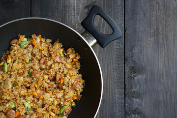 Homemade fried rice with a mixture of eggs, bitter been, and sausage in a frying pan        