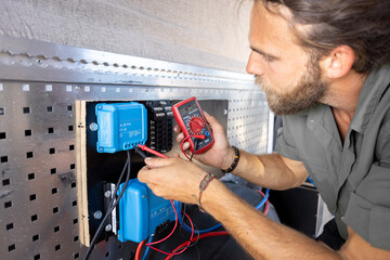 Man testing electronic components with a multimeter - obrazy, fototapety, plakaty