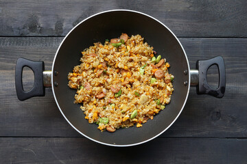 Homemade fried rice with a mixture of eggs, bitter been, and sausage in a frying pan