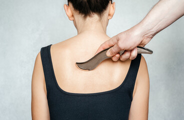 Instrument-assisted soft tissue mobilization, a woman receiving soft tissue treatment on her back with IASTM stainless steel tool