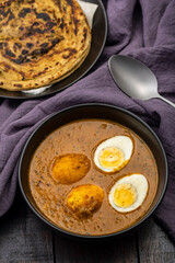 Fried egg curry or Anda Masala served in a bowl with  lachha parantha