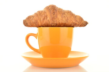 One delicious croissant with chocolate filling on a saucer with a cup, close-up, isolated on white.