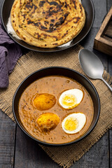Fried egg curry or Anda Masala served in a bowl with  lachha parantha