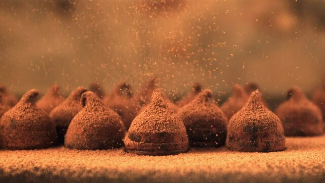 Super slow motion on the truffles is poured cocoa. On a brown background. Filmed on a high-speed camera at 1000 fps.High quality FullHD footage