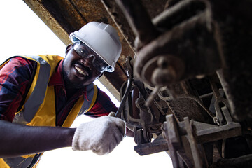 Handsome Africa American industrial engineering maintenance lie and fix engines beside the train at...