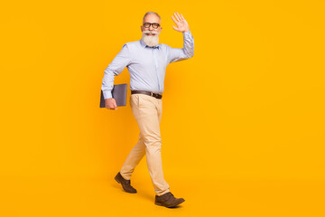 Fototapeta na wymiar Full size photo of cheerful beard elder man hold laptop go wear spectacles blue shirt isolated on yellow color background