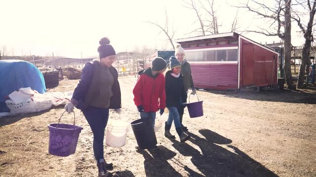 Family With Buckets Walking On Sunny Winter Farm