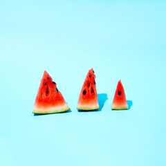 Slices of watermelon lined up on a blue background. Summer composition.