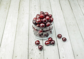 Ripe red cherries in glassware on a light wooden background. Concept of healthy food, diet. Top and side view.