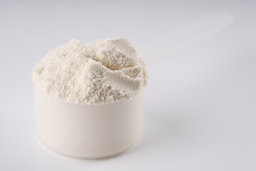 Heap of protein powder on white background. Scoops Of Protein Powder. Measuring spoon and heap of vanilla protein powder.