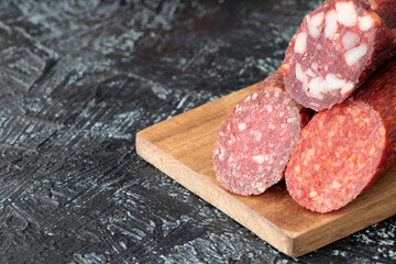 close-up three kinds of different sausages on a cutting board on a black textured background.