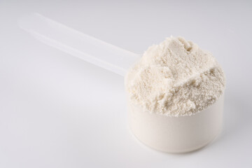 Heap of protein powder on white background. Scoops Of Protein Powder. Measuring spoon and heap of...