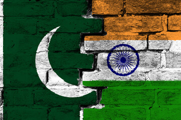 Concept of the relationship between Pakistan and India with two painted flags on a damaged brick...