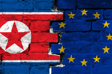 Concept of the relationship between North Korea and the European Union with two painted flags on a damaged brick wall