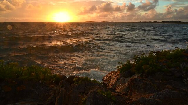Sonnenuntergang am Atlantik in der Bretagne, Frankreich - die Wellen des Meer laufen gegen die Felsen der Insel