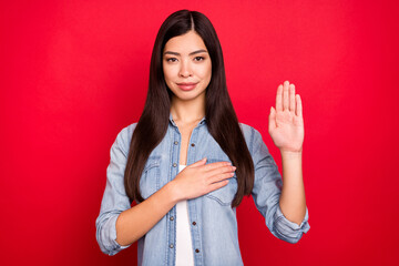 Portrait of attractive calm girl praying showing palm giving promise isolated over bright red color...