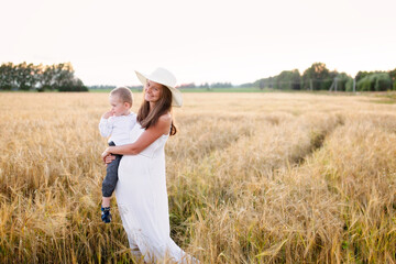 Motherhood. Toddler toddler boy in mom's arms in the field, beautiful summer photo