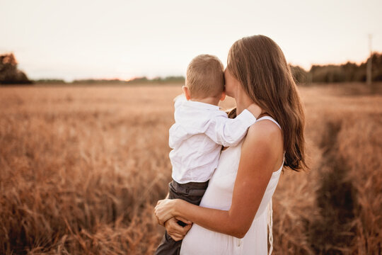 Motherhood. Toddler toddler boy in mom's arms in the field, beautiful summer photo