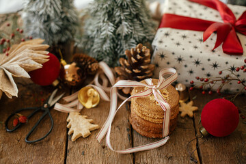 Christmas oatmeal cookies, stylish wrapped gift box, festive decorations on rustic wooden table. Atmospheric stylish christmas composition with healthy cookies and xmas presents. Merry Christmas