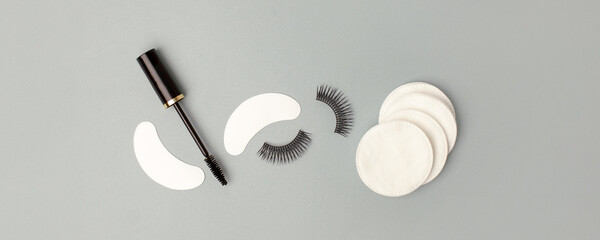 Set for eye lash extension on trendy gray background. Fake eyelashes, mascara brush, cotton pads....
