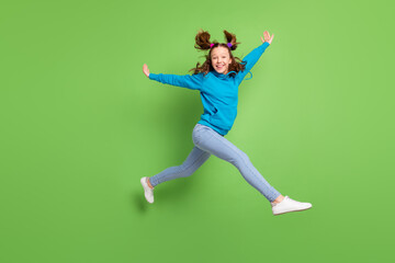Fototapeta na wymiar Full body photo of happy cheerful girl jump up walk fly hair good mood weekend isolated on green color background