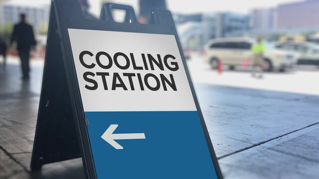 A sign points to pedestrians where the cooling station is during a city heat wave.	