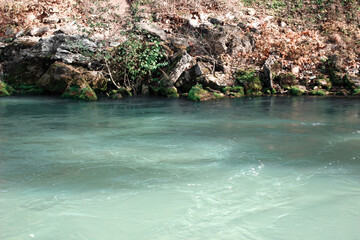 White stones with green moss in a turquoise lake. Nature. Plants in the water.