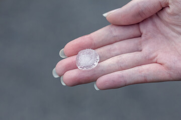 Fototapeta na wymiar Female hand holds hailstone. Summer hail in the hand of a woman. Large hailstones in the hand of man. Hail in a hand