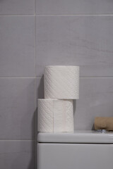 White toilet with some finished rolls of paper and others without touching.