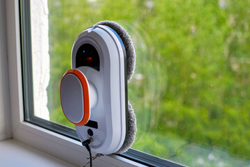 A robot window cleaner. Robot vacuum cleaner cleans a dirty window. Smart robots for cleaning windows, an assistant for the house. The concept of cleaning and polishing windows
