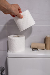White toilet with some finished rolls of paper and others without touching.