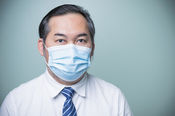 Close up Asian businessman wearing a white shirt with a blue tie and wear a medical mask prevent the coronavirus. Looking at the camera with copy space. Business, Social distances, new normal concept.
