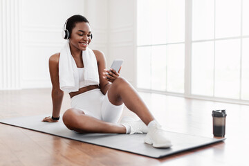 Fitness black lady listening to music during workout break