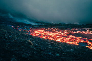 Atmospheric wide-angle view of flowing lava at volcano eruption site in Geldingadalir, Iceland —...
