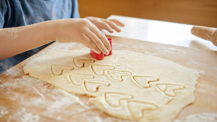 Closeup of little boy cutting biscuit dough with plastic cutter form. Children cooking with...