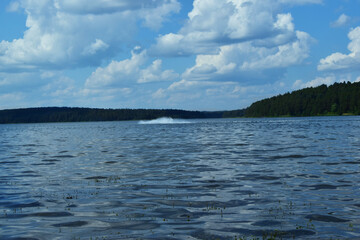 Pond on a sunny summer day with blue clouds and green hills in the background