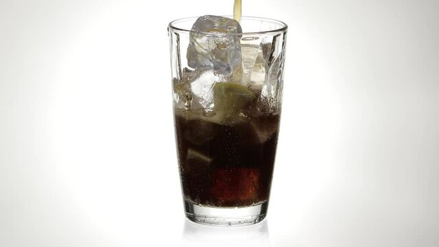 Einschenken eines freistehenden frischen k&uuml;hlen Cola Glas mit Eisw&uuml;rfel und Zitronenschnitz.