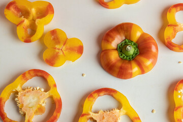 Red, orange yellow sliced bell peppers on white table