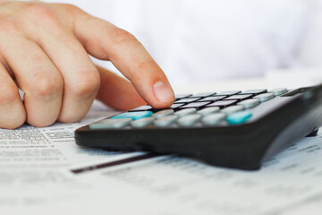 A businessman at an office desk counts on a calculator. business and finance