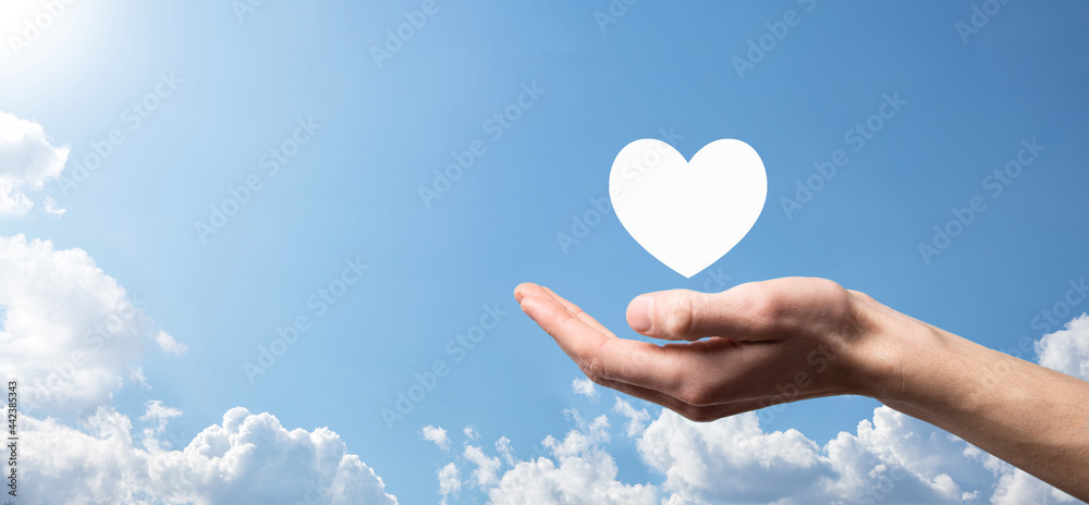 Wall mural Male hand holding heart , like icon on blue background. Kindness, charity, pure love and compassion concept.Banner with copy space