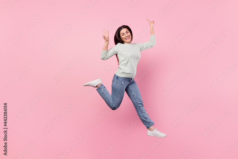 Sticker Full size photo of pretty cheerful nice positive woman jump up make v-sings cool isolated on pink color background