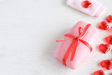 Pink soap, red hearts on a light wooden background. Concept for natural use of funds. Valentine's Day, love for spa