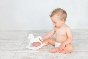 cute baby boy on a white background with a hairstyle and big blue eyes in diapers on a white...