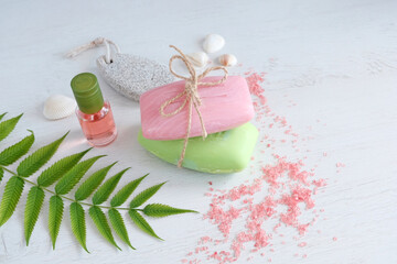 Pink and green soap, on a wooden background. Spa and sauna, beauty salon.Oil in a bottle, pink salt and green leaves background. The concept of the natural use of funds.