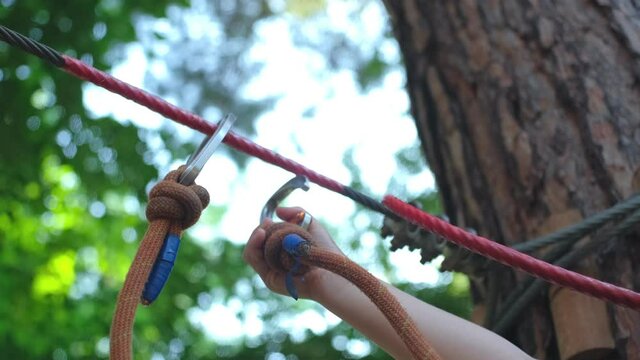 Caucasian Kid Playing in Rope Park Attaching Clip Hook to Metal Safety Cable