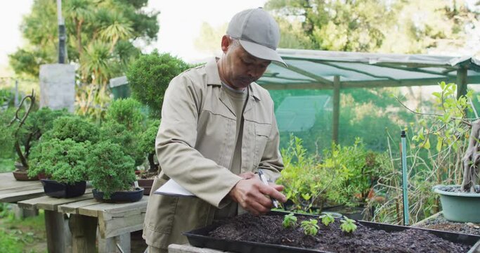 Mixed race male gardener making notes at garden center