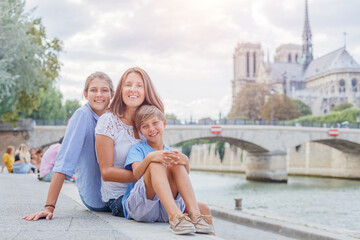 Fototapeta na wymiar Happy family having fun near Notre-Dame cathedral in Paris. Tourists enjoying their vacation in France.