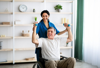 Post-stroke rehabilitation. Female physiotherapist helping elderly male patient in wheelchair to make exercises at home