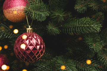 Fir tree with New Year decorations. Glowing gold and red Christmas ornaments with copy space.